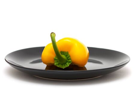 Half of yellow pepper on a black plateの写真素材