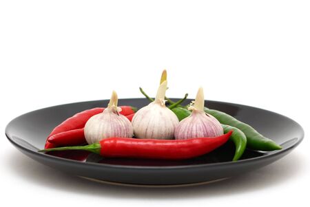 Three garlics with chili peppers on a plateの写真素材