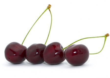 Four cherries with green stems isolated on whiteの写真素材