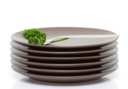 Stack of brown round plates with fork and parsley (with sample text) の写真素材