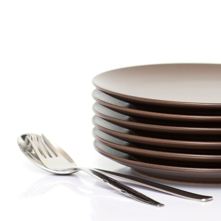 Stack of brown round plates with spoon and fork (with sample text)の写真素材