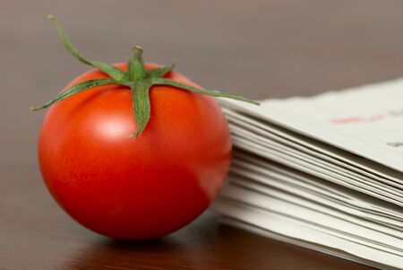 Red tomato on a table with a newspappersの写真素材