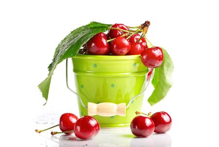 Fresh cherries with green leaves and drops in green bucket isolated on white の写真素材