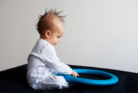 Baby with mohawk sitting and playingの写真素材