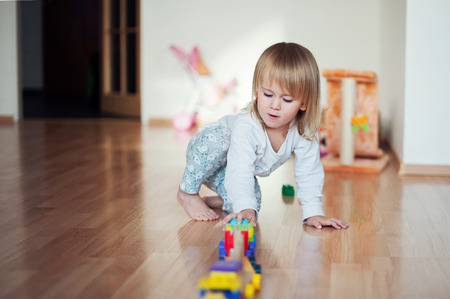 Little girl playing with train. Toddler kid play with trains and cars. Educational toys for preschool and kindergarten child. Girl build toy railroad at home or daycare.の写真素材