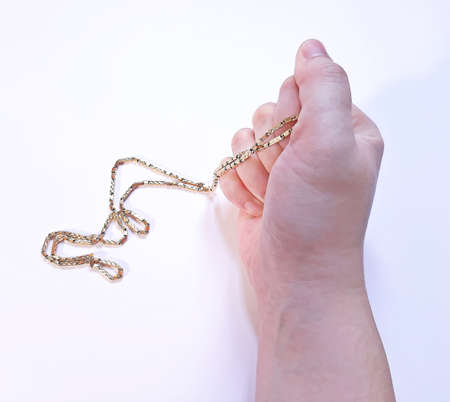 Gold necklace in a firmly hand fistの写真素材