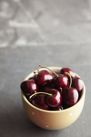 Cherries in a green bowl on a slate worktop, taken with natural side lighting.の写真素材