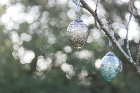 Christmas glass decoration haning outside on the branch of a tree. Back lighting has caused a bokeh...