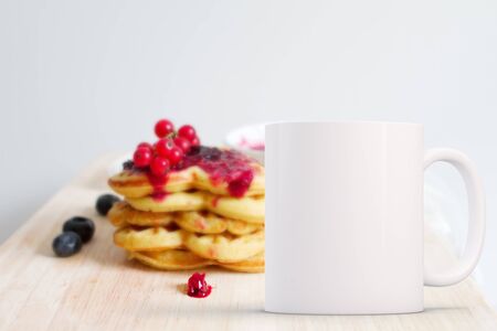 White blank coffee mug mock up, in front of a stack of pancakes with fruit on, add custom design or quote on to the mug.の写真素材