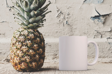 White blank coffee mug mock up, next to a pineapple, add custom design or quote on to the mug.の写真素材