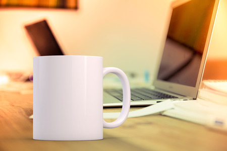 White blank coffee mug mock up, on a desk next to a laptop, add custom design or quote on to mugの写真素材