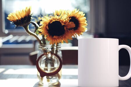 White blank coffee mug mock up, next to a vase of sunflowers, add custom design or quote on to the mug.の写真素材