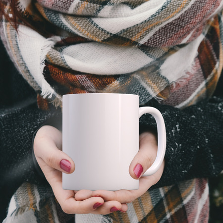 Womans hands holding a white blank coffee mug, Winter theme mock up. Perfect for businesses selling mugs, just overlay your quote or design on to the image.の写真素材