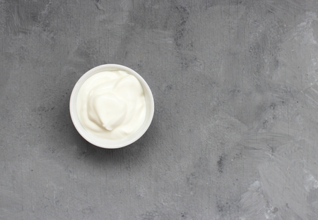 White cream in a white jar on a gray background.の写真素材