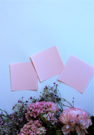 Bouquet of pink flowers (Ranunculus) and pink sheets of writing paper isolated on white background....