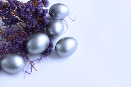 Silver Easter eggs on a white background with purple flowers. Copy space.の写真素材