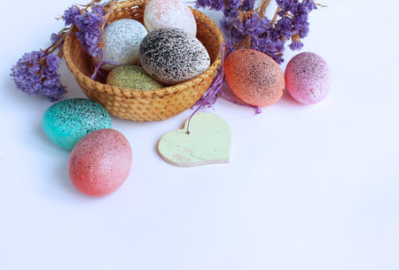 Colorful easter eggs in basket and flowers on white background.