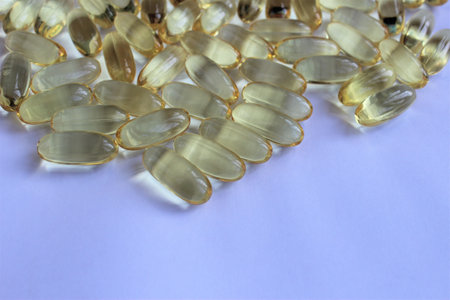 Close up of a lot of fish oil capsules on a purple background