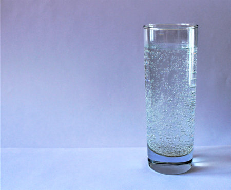 Glass of water with bubbles on a blue background. Copy space.の写真素材