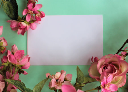 Blank paper with pink flowers on green background. Place for your text.の写真素材