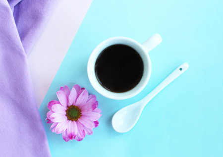 Cup of coffee with flower on blue and purple background, flat layの写真素材