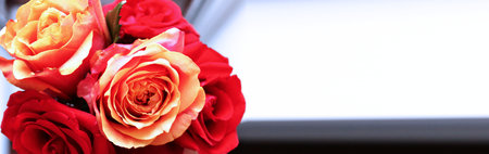 Bouquet of red and orange roses on a window sill.