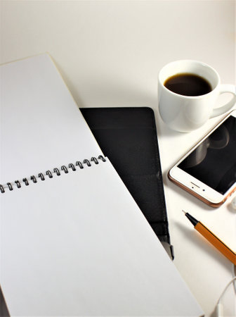 Office table with notepad, smart phone and cup of coffee.の写真素材
