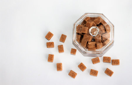 Cubes of brown sugar in a glass bowl on a white backgroundの写真素材