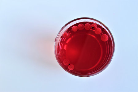 Red liquid in a glass on a white background, close-up