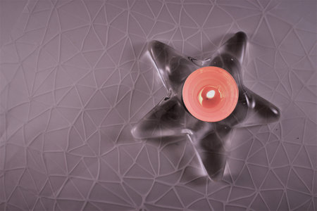 Candle in the shape of a star on the background of a geometric patternの写真素材