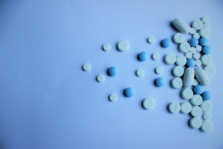 Blue and white pills on a blue background. Focus on foreground.の写真素材