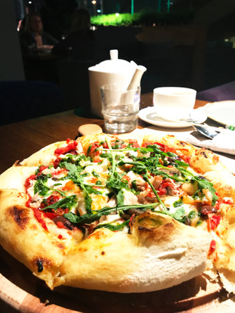 Pizza on a wooden table in a restaurant. Italian cuisine.