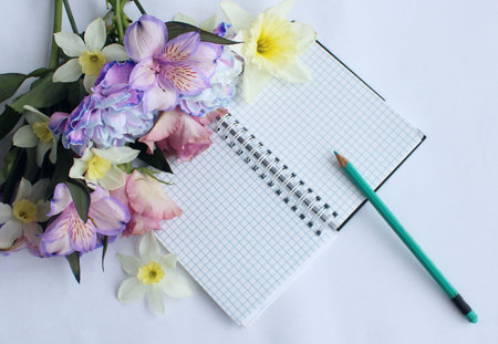 Bouquet of spring flowers and a notebook on a white background