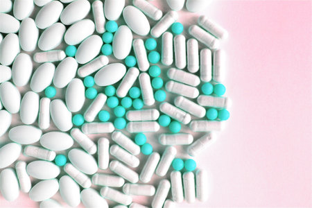 Pills and capsules on a pink background. Close-up.
