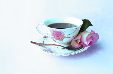 Cup of tea with pink rose on white background, vintage style
