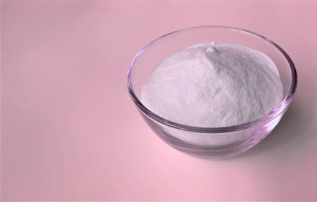 Spa salt in a glass bowl on a pink background with copy space