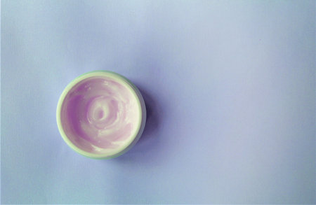 Top view of a jar of cream on a purple background.