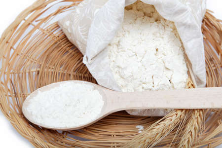 Flour and wheat grain with wooden spoon on a wicker basket の写真素材