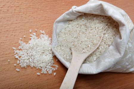 Rice in a bag and a spoon on a wooden table.の写真素材