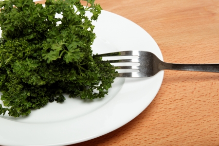 fresh bunch of parsley on the plate with a fork on a wooden table.の写真素材