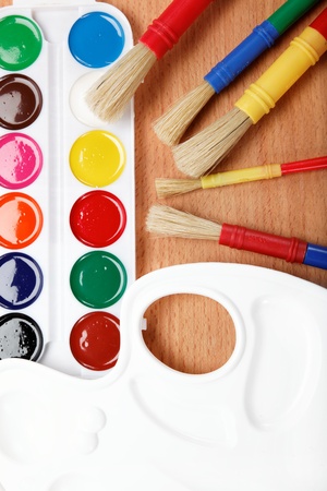 Paint, palette and brushes on a wooden table の写真素材