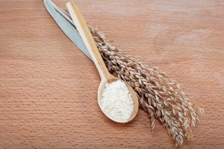 Corn flour in a wooden spoon and ear on wooden table.の写真素材