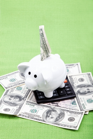 Piggy bank with a calculator and American dollar bills on the green cloth.の写真素材
