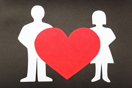 Silhouettes of men, women and heart cut out of paper on a black background. Happy couple in love.の写真素材