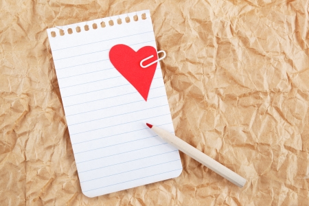 Sheet of notebook with a heart and pencil on crumpled paper. Valentines note.の写真素材