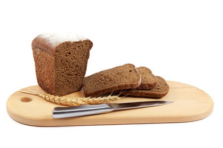 Fresh bread with ears and a knife of wheat on the wooden cutting board.