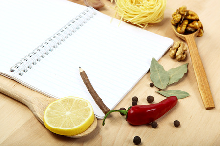 Notebook for recipes, vegetables and spices on wooden table.の写真素材