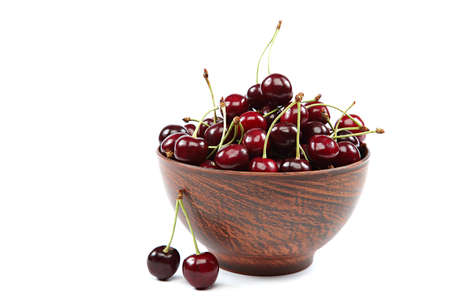 Fresh cherries in a wooden bowl isolated on a white background.