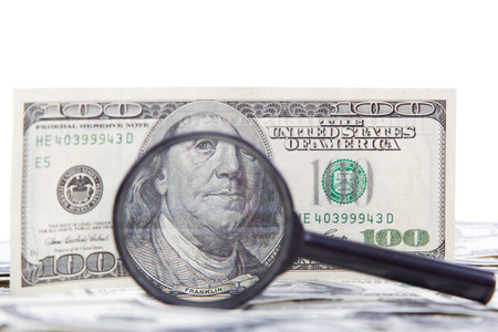 Hundred dollar bill and magnifying glass isolated on a white background.の写真素材