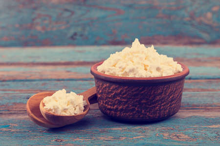 Fresh cottage cheese in a ceramic dish and spoon on painted blue wooden boards.の写真素材